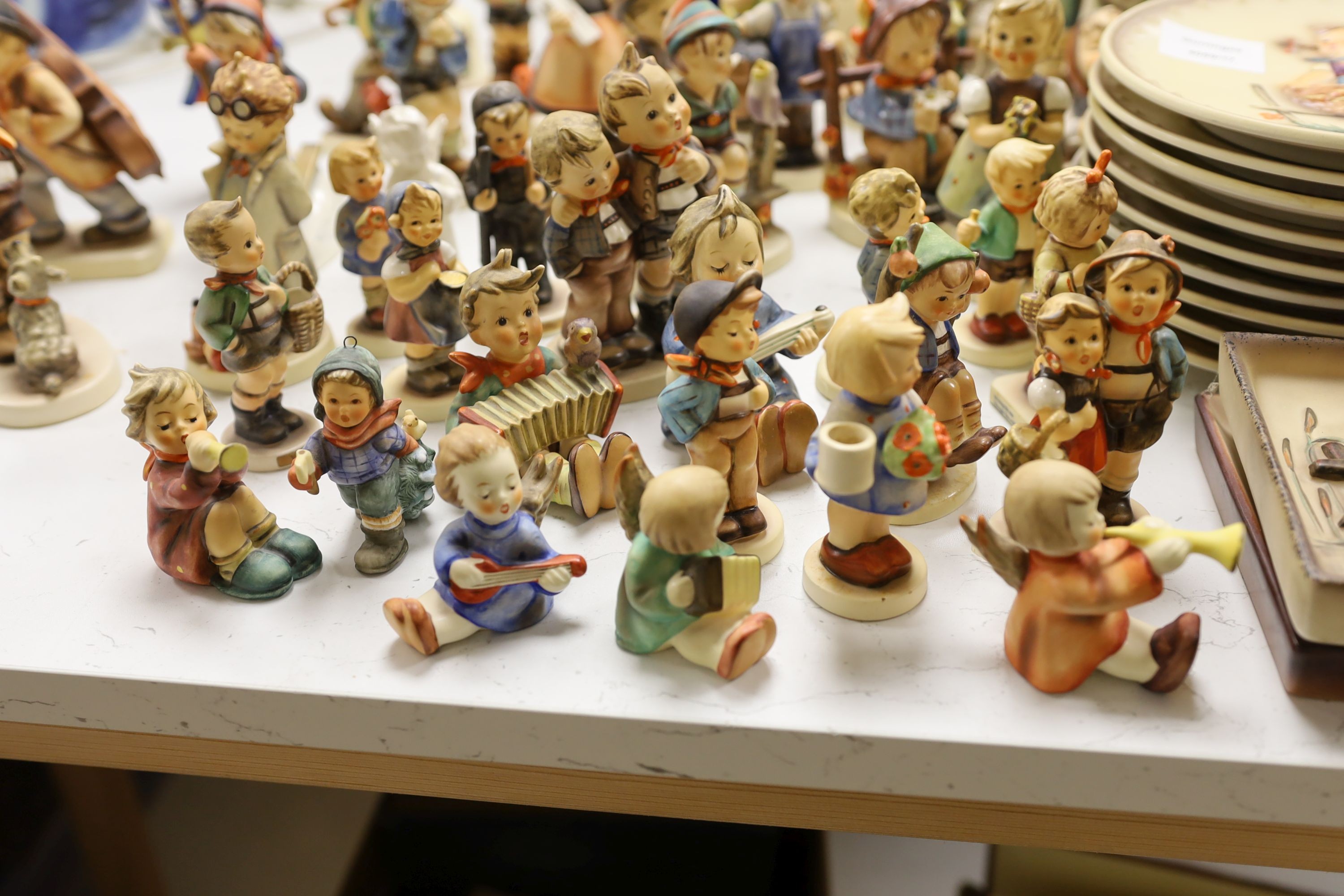 A large collection of Hummel pottery figures, approximately 70 including skier and two similar plaques, some with boxes.